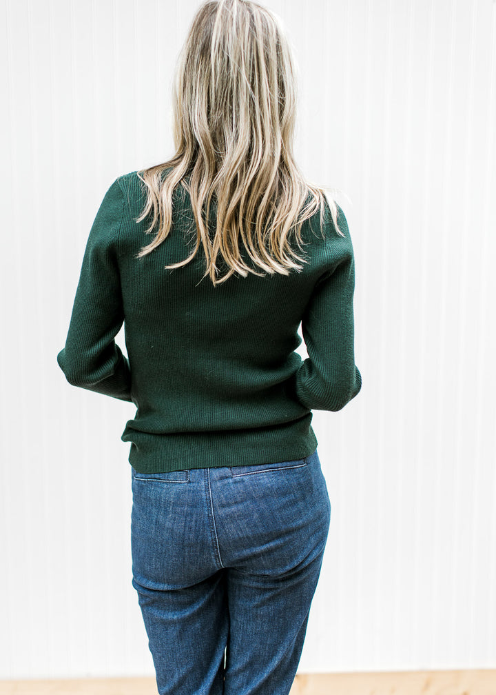 Back view of Model wearing a lightweight green ribbed top with a turtleneck and long sleeves. 