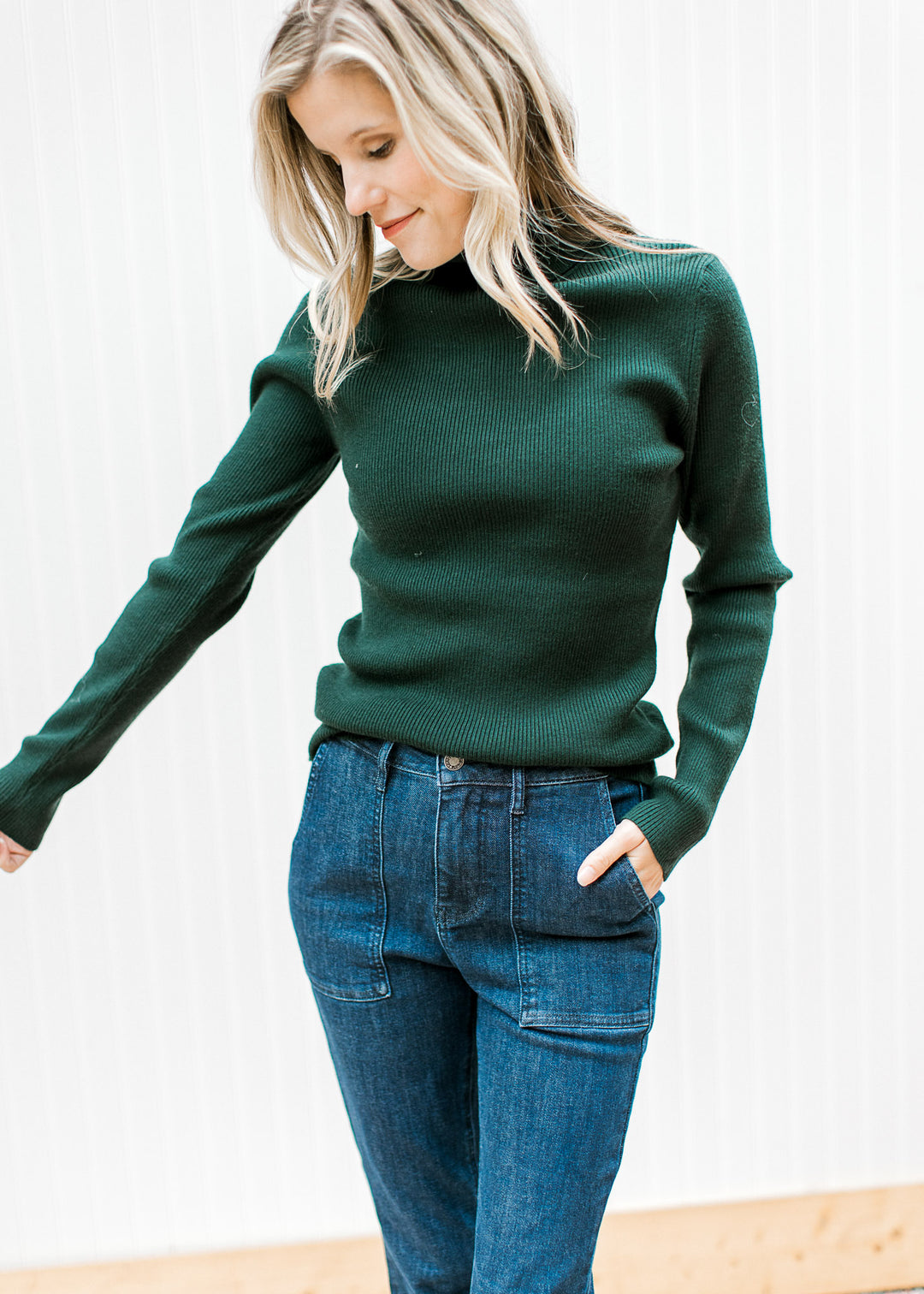 Model wearing a green ribbed top with a turtleneck, long sleeves and a lightweight material. 
