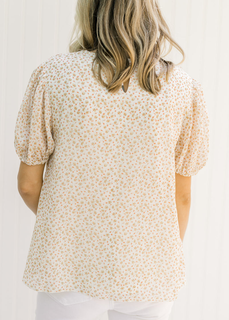 Back view of Model wearing a pleated ivory top with a microfloral patter and short sleeves. 