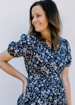 Model wearing a navy midi with white flowers, elastic waist, short sleeves and an elastic waist. 