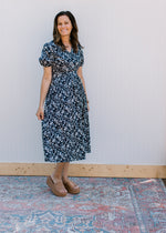 Model wearing brown wedges with a navy midi with white flowers and an elastic waist.