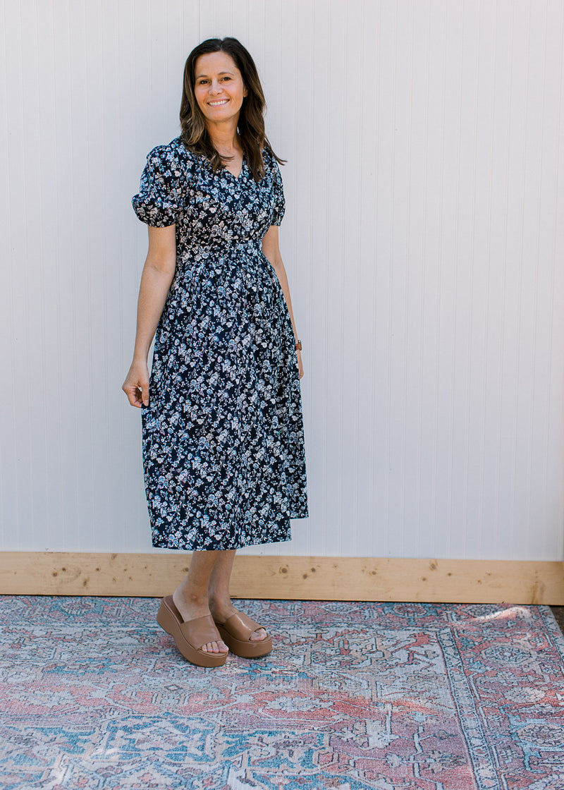 Model wearing brown wedges with a navy midi with white flowers and an elastic waist.