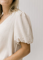Close up view of bubble short sleeves on a model wearing an oatmeal colored top. 