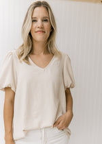 Model wearing white jeans with an oatmeal colored top with short sleeves and a graduated hem. 