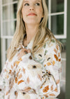 Model wearing a white long sleeve jacket with fall floral, a quilted fabric and long sleeves.