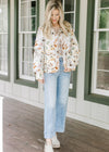 Model wearing jeans, mules and a white quilted jacket with fall floral and long sleeves.