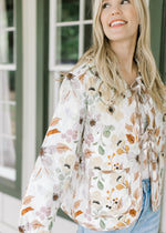 Model wearing a white quilted jacket with fall floral, a flap collar with ruffle and long sleeve.