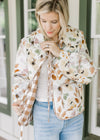 Model wearing jeans with a white quilted jacket with fall floral, long sleeves and tie closure.