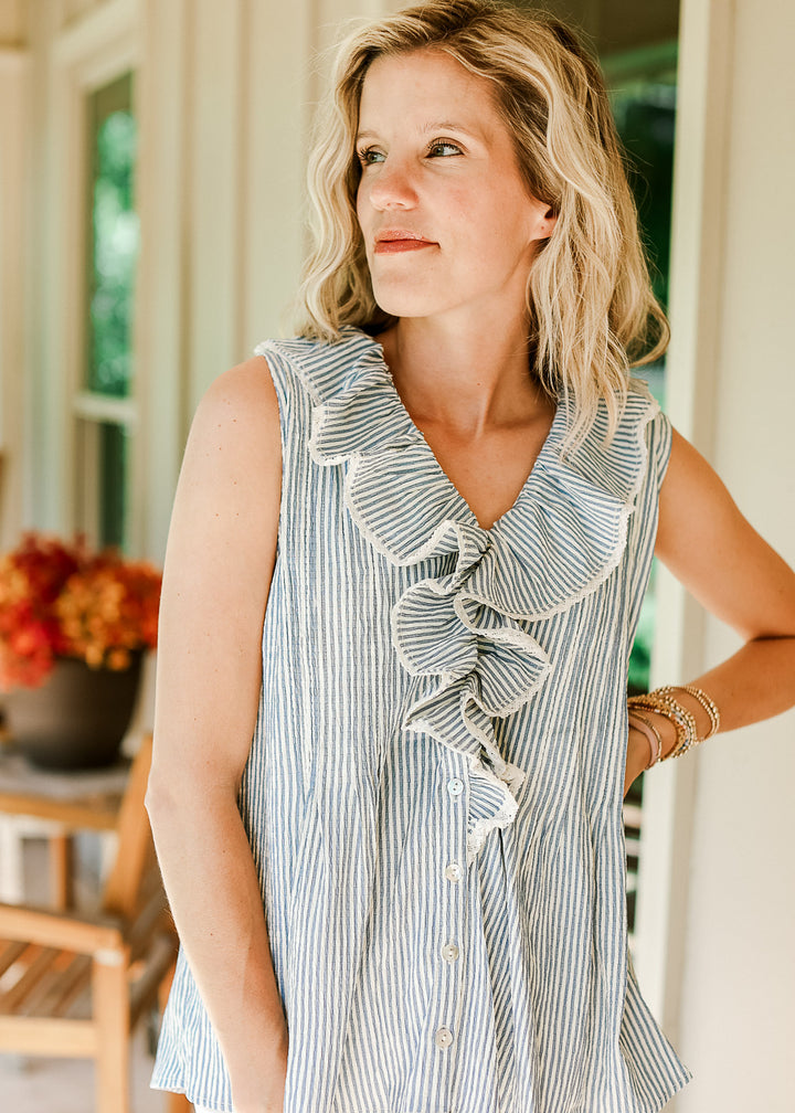 Model wearing a sleeveless top with off-white and blue stripes and exaggerated flap collar. 