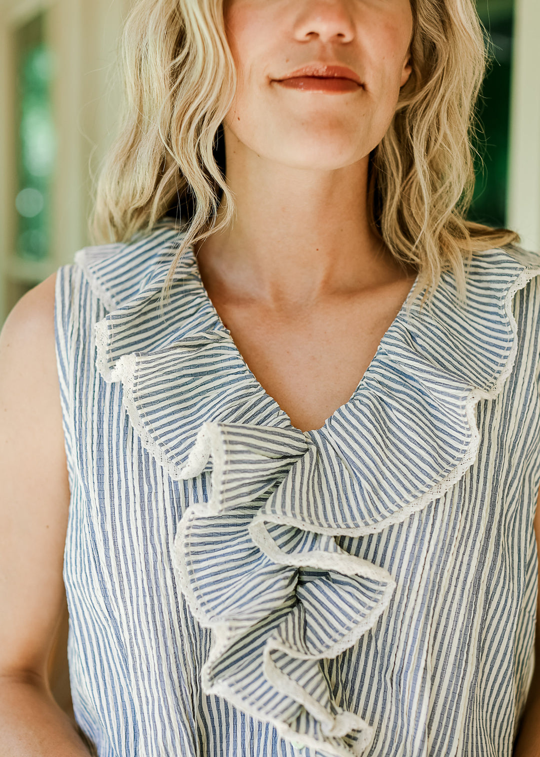 Close up of v-neck and exaggerated flap collar with lace on a off white and blue striped top.