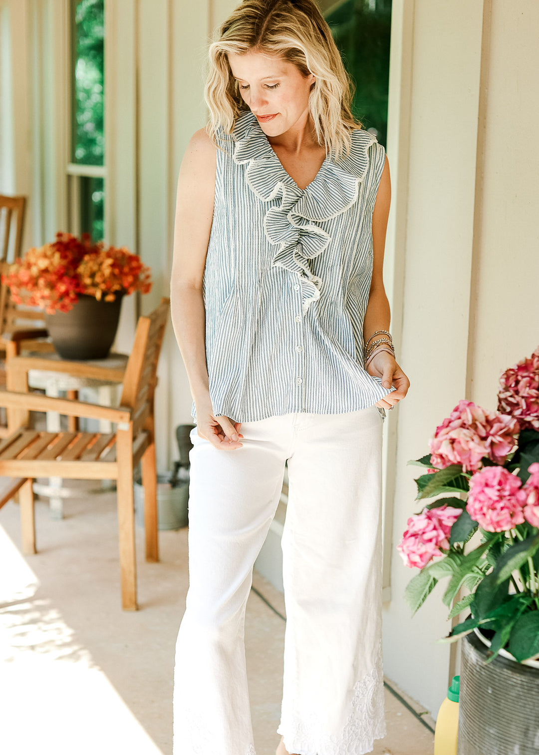 Model wearing pants and a sleeveless top with off-white and blue stripes and flap collar with lace.