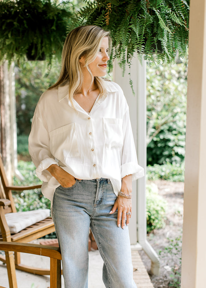 Model wearing a bright white button up top with double patch pockets and cuffed long sleeves. 