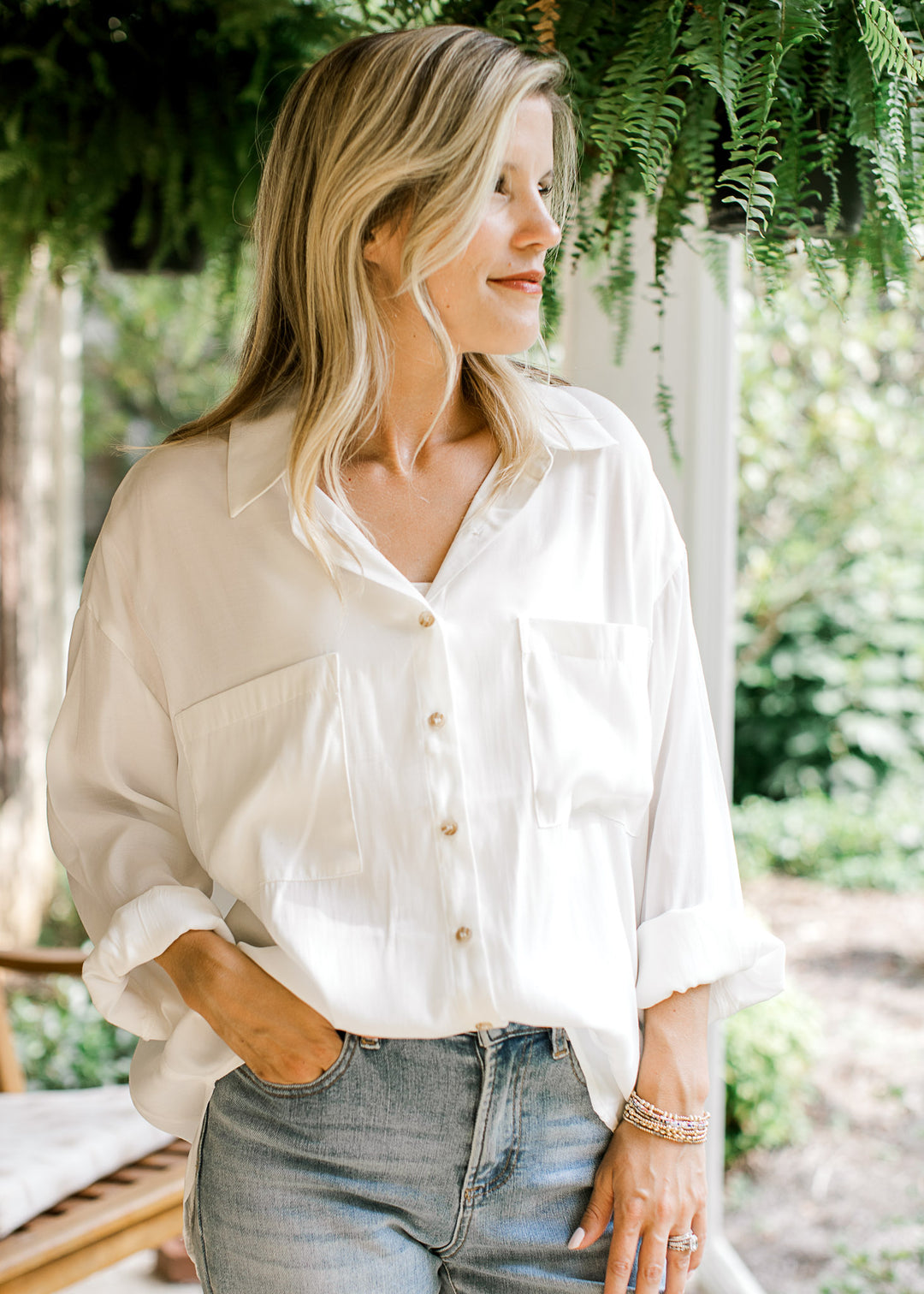 Model wearing a bright white button up top with double patch pockets and long sleeves. 