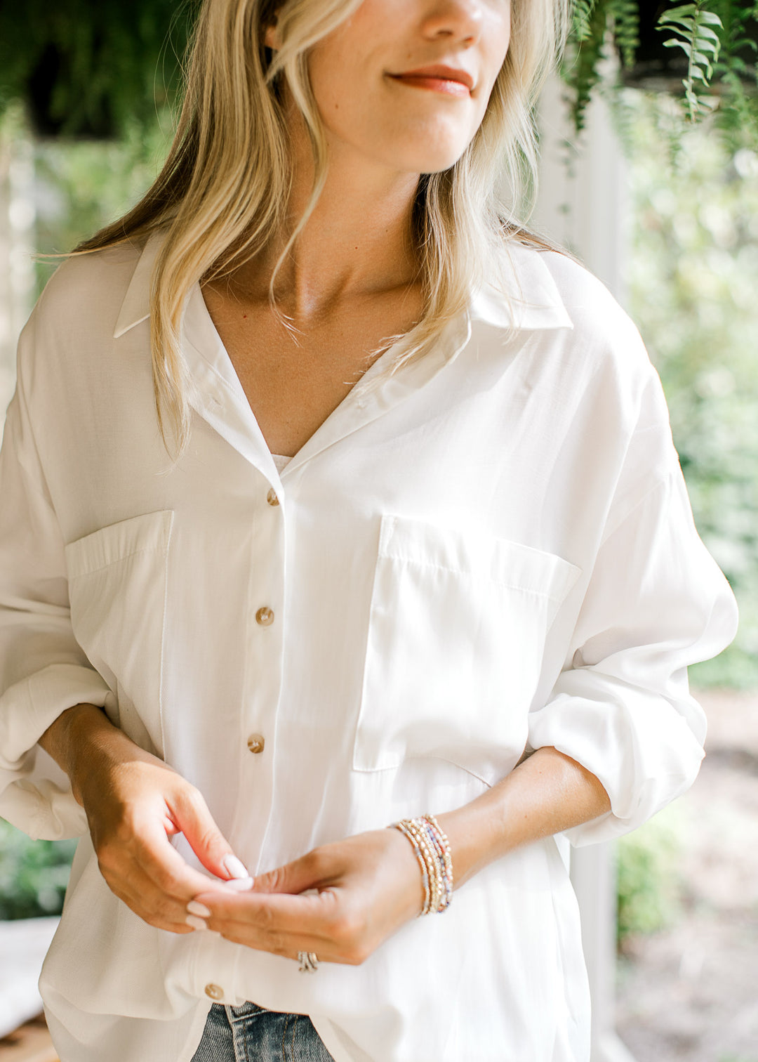 Close up of  patch pockets on a long sleeve white button up top with collar. 