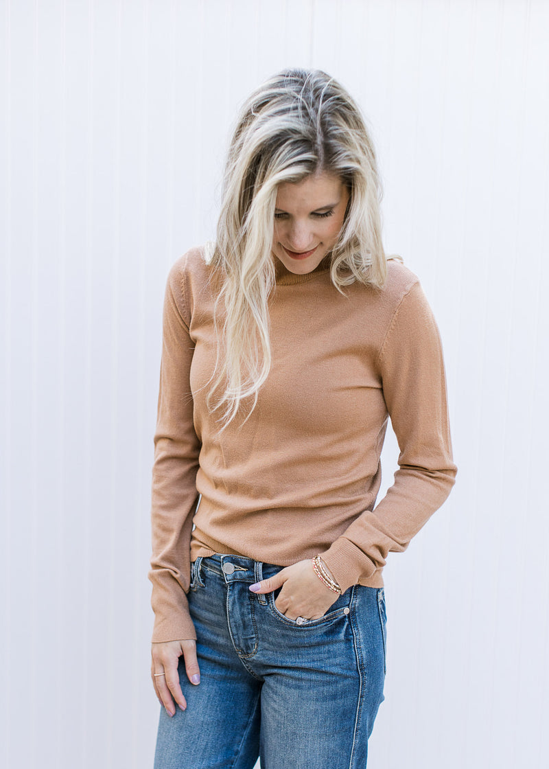 Model wearing a clay colored sweater with long sleeves, mocked neck and lightweight material. 