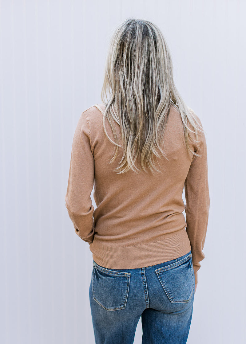 Back view of Model wearing a clay colored sweater with long sleeves and a mocked neck 