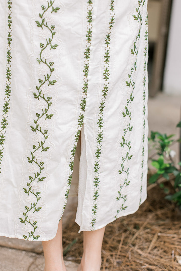 Close up of front slit on a cream midi dress with cream and olive floral and short sleeve.