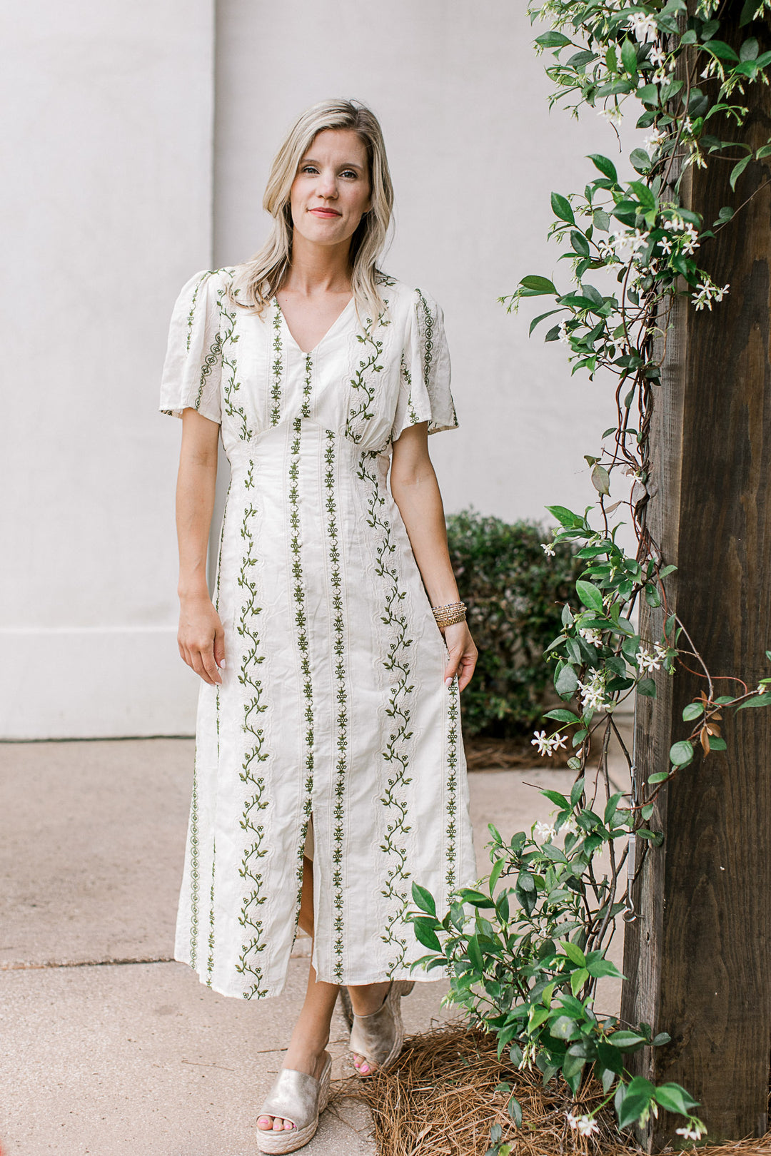 Model wearing wedges and a cream midi with olive and short sleeves with pleated shoulders.