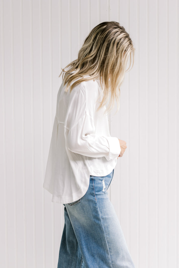 Model wearing jeans with a white button down top with a hi-low cut, collar and a polyester material.