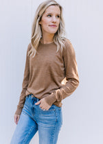Model wearing a camel colored lightweight sweater with a round neck and long sleeves. 