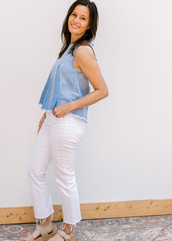 Model wearing white jeans and a lightwash denim top with a raw edge hem and a hidden zipper. 