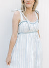 Model wearing a fully lined blue and cream striped maxi with blue piping trim and tie straps. 