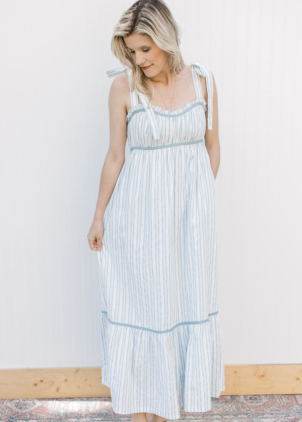 Model wearing a lined blue and cream striped maxi with blue piping trim and tie spaghetti straps. 