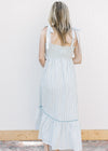 Back view of Model wearing a blue and cream striped maxi with blue piping and a smocked back. 