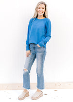 Model wearing jeans and a blue sweater with a ribbed detail at shoulder, crew neck and long sleeves.