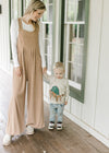 Model, with little boy, wearing a light brown jumpsuit with a pouch pocket and wide legs. 