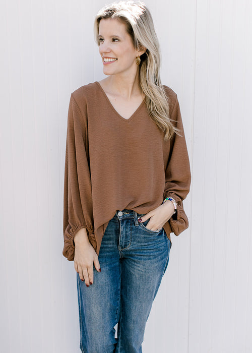 Model wearing a brown top with a v-neck, 3/4 bubble sleeves and a polyester material. 