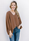Model wearing jeans and a brown polyester top with a v-neck, 3/4 bubble sleeves. 