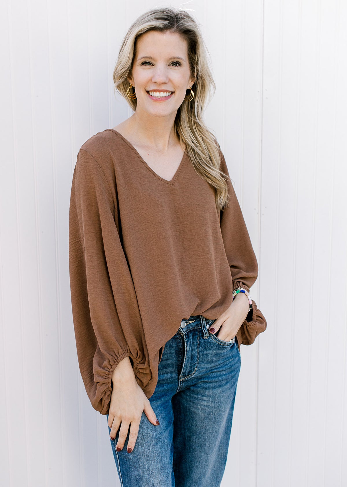 Model wearing jeans and a brown polyester top with a v-neck, 3/4 bubble sleeves. 