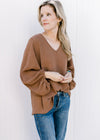 Model wearing a brown oversized v-neck top with 3/4 bubble sleeves and a polyester material. 