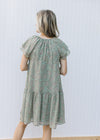 Back view of Model wearing a sage dress with paisley design, layered short sleeves and v-neck. 