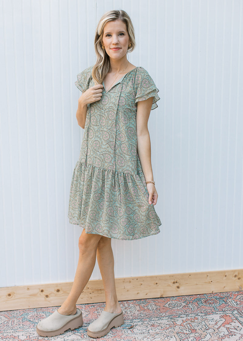 Model wearing mules with a sage dress with paisley design, layered short sleeves and v-neck. 