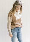 Model wearing jeans with a cream, camel and taupe sweater with ribbed detail, turtleneck and zipper.