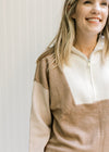 Close up of zipper and ribbed detail on bodice of a cream, camel and taupe sweater with turtleneck.