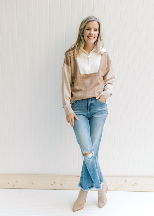 Model wearing a cream, camel and taupe sweater with a ribbed bodice, neck and cuff and 1/4 zipper. 