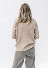 Back view of Model wearing a taupe sweater with a honeycomb pattern, turtle neck and long sleeves.