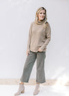 Model wearing wide leg pants, booties and a taupe long sleeve sweater with a honeycomb pattern. 