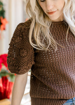 Model wearing a short sleeves sweater with a rich brown color and knit open weave material.