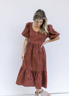 Model wearing a v-neck, wine midi dress with a ribbed bodice, short puff sleeves and pockets. 