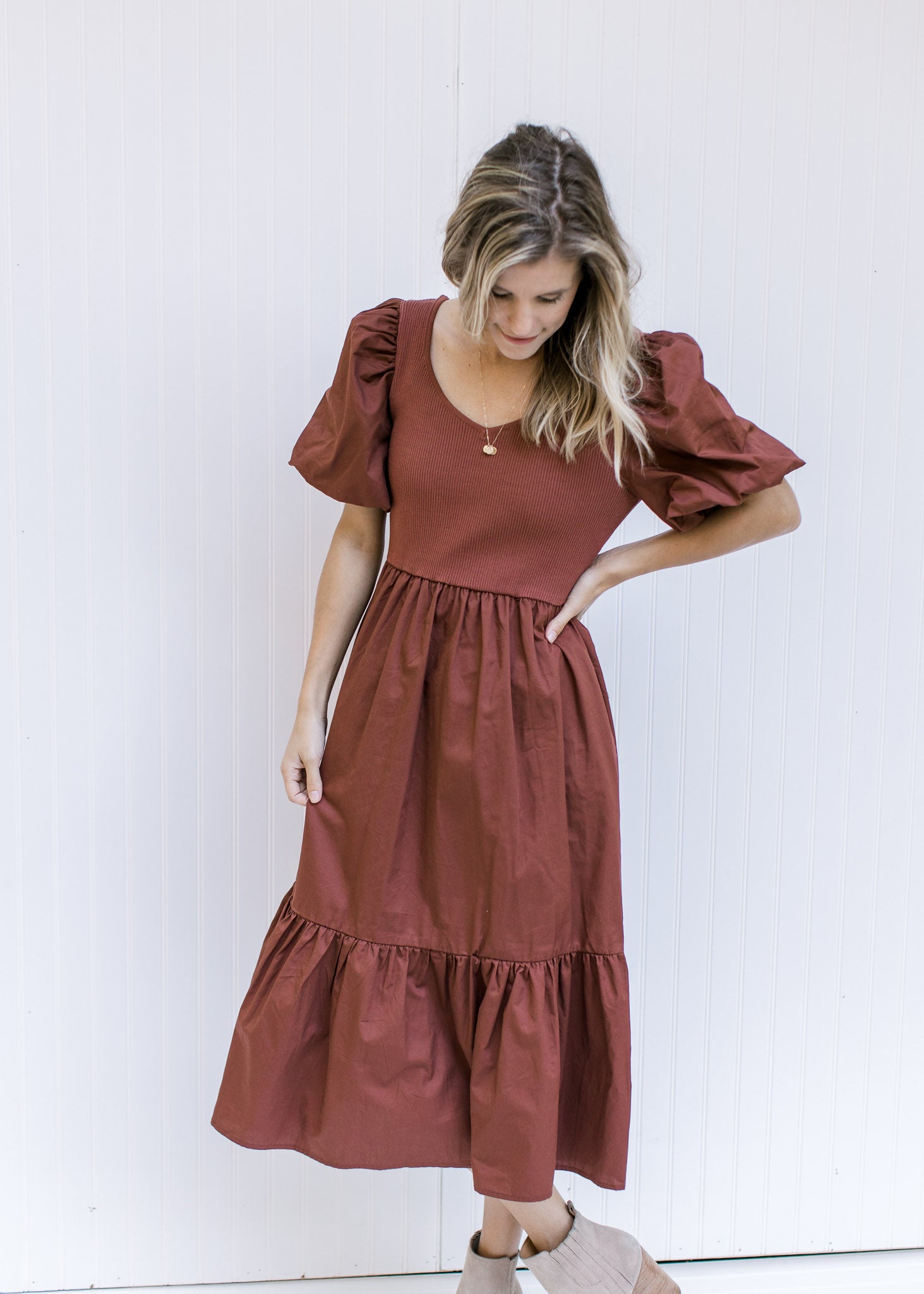 Model wearing a v-neck, wine midi dress with a ribbed bodice, short puff sleeves and pockets. 