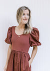 Close up of ribbed bodice and short puff sleeves on a wine midi dress with a v-neck. 