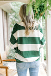 Back view of Model wearing a green and cream striped sweater with long sleeves and a collar. 