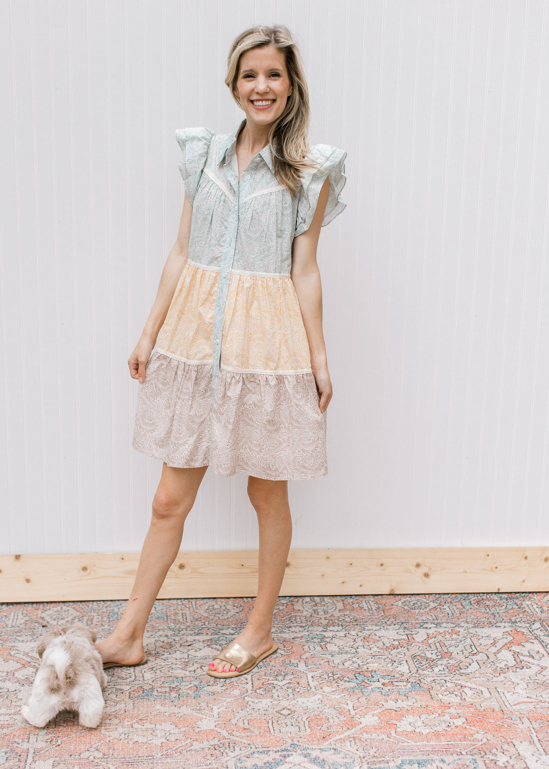 Model wearing flats with a sage, mustard and khaki floral dress with button front and a lace detail.