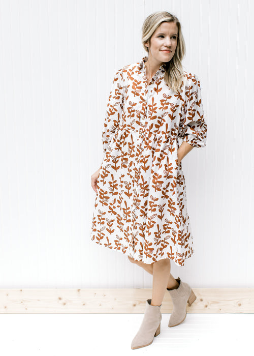Model wearing booties and a lined white midi dress with a brown leaf pattern and bubble sleeves.
