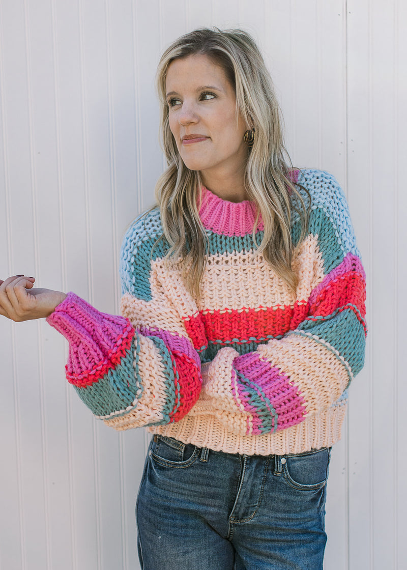 Model wearing a chunky color block knit sweater with long sleeves and a round neck. 