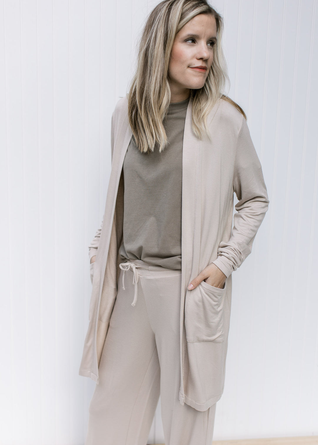 Model wearing a sage top with an open front kimono with patch pockets and long sleeves. 